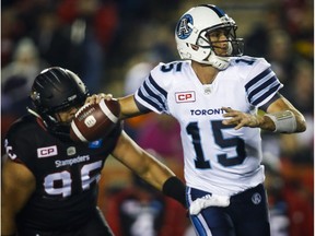 Toronto Argonauts quarterback Ricky Ray looks for a receiver as Calgary Stampeders' Zach Minter defends during first half CFL football action in Calgary, Friday, Oct. 21, 2016.