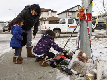 A woman and her children pay their respects at a memorial in front of a home where three bodies were discovered on Monday in Spruce Grove, Alta., on Tuesday, Dec. 20, 2016.