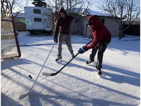 Austin Sarafinchan (right) plays a game of shinny on his backyard rink with his friend Alex Craner (left) on Sunday, December 11, 2016  in Edmonton.
