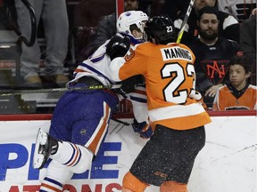 Edmonton Oilers captain Connor McDavid gets checked along the boards by Philadelphia Flyers' Brandon Manning Thursday in Philadelphia. (AP Photo)
