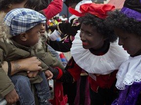Children watch the arrival of Sinterklaas, the Dutch version of Santa Claus, and his sidekick Zwarte Piet, or Black Pete, in Amsterdam, The Netherlands, on Nov. 17, 2013. The character, which is represented with blackface, an Afro and large, red lips, has continued to cause controversy around the world.
