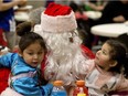 Sisters Ocean, 4, and Zoe, 2, visit with Santa Claus during the Thrive Family Church's Community Christmas Dinner at Boyle Street Plaza on Dec. 25, 2016. Their mother, Robbien Sasky, said the family of seven were grateful for the feast after a difficult year.