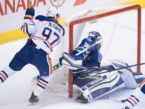 Edmonton Oilers' Connor McDavid, left, scores against Vancouver Canucks' goalie Ryan Miller during the second period of an NHL hockey game in Vancouver, B.C., on Friday October 28, 2016.