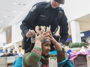 Const. Ashleigh Ness helps Nardo Gezay, 6, with her crown during the first CopShop event at Londonderry Mall in Edmonton on Dec. 7, 2016.