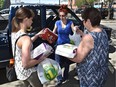 Volunteers Erica Waye (left) and Tina MacPerson receive donations from Shayna Lavallee at the Edmonton Emergency Relief Services Society, which co-ordinated donation efforts for the Fort McMurray fire evacuees.