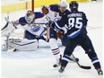 Edmonton Oilers goaltender Cam Talbot (33) gets a pad on Winnipeg Jets' Mathieu Perreault's (85) shot as Oilers' Oscar Klefbom (77) defends during third period NHL action in Winnipeg on Thursday, December 1, 2016.