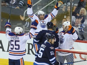 Edmonton Oilers left winger Patrick Maroon (c) celebrates his second period goal against the Winnipeg Jets with center Mark Letestu (l) and right winger Zack Kassian as Winnipeg Jets defenceman Paul Postma and center Mark Scheifele look on during NHL hockey in Winnipeg, Man. Thursday December 01, 2016. Brian Donogh/Winnipeg Sun/Postmedia Network