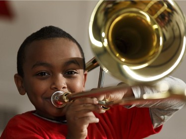 Hanania Zelleke, 9, a music student in the Edmonton Symphony Orchestra and the Winspear Centre for Music's YONA-Sistema music program, plays his new trombone for the first time at St. Alphonsus Catholic School in Edmonton, Alberta on Wednesday, December 7, 2016.