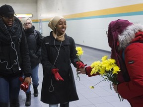 Nakita Valerio (right) with the Alberta Muslim Public Affairs Council, hands out flowers to women wearing hijabs at the University of Alberta LRT station on Wednesday, Dec. 7, 2016. The Edmonton police hate crimes unit has a suspect in custody following a Nov. 8 incident where a man threatened two Muslim women with a noose at the LRT station.