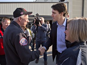 Prime Minister Justin Trudeau shakes hands with Fort McMurray fire chief Darby Allen as Alberta Premier Rachel Notley (right) looks on in Edmonton, on May 13, 2016, before a flight to Fort McMurray. Trudeau made the visit to see first-hand the devastation caused by the wildfire that forced the evacuation of the city.