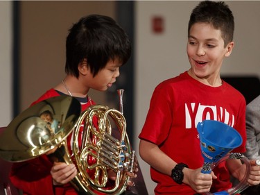 Khoan Nguyen, 11, (left) and Zander Ross, 10, music students in the Edmonton Symphony Orchestra and the Winspear Centre for Music's YONA-Sistema music program, exchange plastic practice instruments for real instruments during a ceremony at St. Alphonsus Catholic School in Edmonton, Alberta on Wednesday, December 7, 2016.