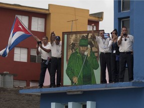 Men stand on a roof to watch the funeral procession carrying Fidel Castro's ashes leave Santa Clara, Cuba, on Dec. 1, 2016. Castro's ashes are on a four-day journey across Cuba from Havana to their final resting place in the eastern city of Santiago.