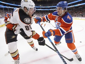 Anaheim Ducks' Ondrej Kase (86) is checked by Edmonton Oilers' Kris Russell (4) during third period NHL action in Edmonton, Alta., on Saturday, December 3, 2016.