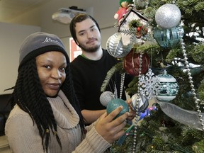 Orama Amadi (left) and Mateo Roldan decorate a Christmas tree at NAIT's International Centre.