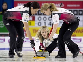 Team Jones skip Jennifer Jones, centre, delivers a stone as lead Dawn McEwen, right, and second Jill Officer sweep at the Canada Cup of Curling final against Team Homan in Brandon, Man., on Sunday, Dec. 4, 2016.