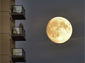 Two people on their balcony watch the FC Edmonton game at Clark Field as the waxing gibbous (94% full) moon rises behind them in Edmonton, Wednesday, September 14, 2016. Ed Kaiser/Postmedia (Standalone Photo) ***Year in Review