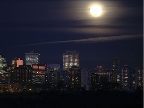 The full moon shines on top of the Edmonton skyline.