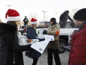Volunteer Tanner Hawtin, right, hands turkeys to Erin Rawe and Jessica Hann outside of the Edmonton Expo Centre at Northlands on December 17, 2016.