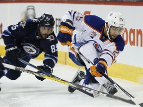 Winnipeg Jets' Mathieu Perreault (85) goes down as Edmonton Oilers' Darnell Nurse (25) clears the puck during second period NHL action in Winnipeg on Thursday, December 1, 2016.