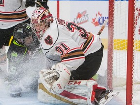 Edmonton Oil Kings forward Scott Atkinson, left, crashes Calgary Hitmen goalie Cody Porter during second period WHL action at Rogers Place on January 1, 2017.