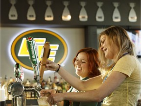 Bartenders/servers Josie Wilson (left) and Shannon Kennedy pour beer during the grand opening of Edmonton Eskimos Sports Bar at Edmonton International Airport in Nisku on Wednesday, Jan. 25, 2017.