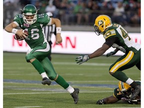Brett Smith, seen here with the Saskatchewan Roughriders, dodges the tackle from Edmonton Eskimos defenders Ryan Hinds (34) and Deon Lacey (40) in Fort McMurray on June 13, 2015. (The Canadian Press)