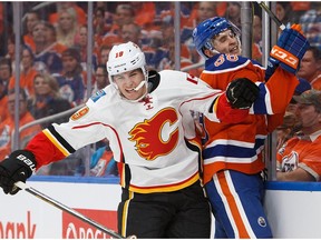 Brandon Davidson #88 of the Edmonton Oilers is taken to the boards by Matthew Tkachuk #19 of the Calgary Flames on October 12, 2016 at Rogers Place.