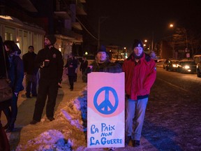 People stand with a peaceful sign near the Québec City Islamic cultural center after a shooting occurred in the mosque on Sainte-Foy Street in Quebec city on January 29, 2017.