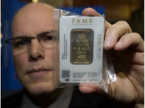 Const. Robert Wellon with the Edmonton Police Service northwest division's criminal investigation section holds a counterfeit gold bar being sold in the city, during a press conference at police headquarters in Edmonton on Jan. 9, 2017.