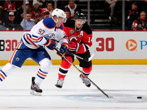 Connor McDavid of the Edmonton Oilers takes the puck as Adam Henrique of the New Jersey Devils defends in the first period on February 9, 2016 at Prudential Center in Newark, New Jersey.