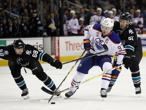 Connor McDavid #97 of the Edmonton Oilers skates between Melker Karlsson #68 and Justin Braun #61 of the San Jose Sharks at SAP Center on January 26, 2017 in San Jose, California.