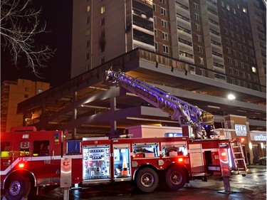 Firefighters use the aerial ladder to access the top of the parkade were above them fire caused damage to a number of suites to an apartment complex on Jasper Ave. and 118 St. in Edmonton, Thursday, Jan. 19, 2017.