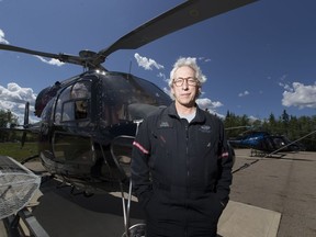 Paul Spring, a helicopter pilot and owner of Phoenix Heli-Flight, poses next to one of his helicopters south of Fort McMurray, Alta. on June 3, 2016.