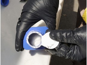 In this June 27, 2016, photo provided by the Royal Canadian Mounted Police, a member of the RCMP opens a printer ink bottle containing the opioid carfentanil imported from China, in Vancouver.