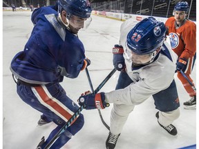 Jordan Eberle (14) and Matt Hendricks (23) battle for a puck along the boards as defenceman Kris Russell looks on. The Edmonton Oilers practiced at Rogers Place in Edmonton on January 8, 2017 preparing for their next game against New Jersey.