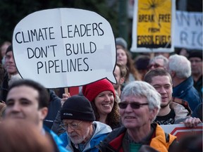 A woman holds a sign during a protest and march against the Kinder Morgan Trans Mountain Pipeline expansion, in Vancouver, B.C., on Saturday Nov. 19, 2016.