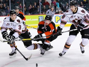 Calgary Hitmen Jakob LaPointe, left, and Tyler Mrkonjic try to force Medicine Hat Tigers forward Mason Shaw off the puck at the Scotiabank Saddledome in Calgary on Dec. 28, 2016. (Gavin Young)