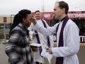Rev. Nick Trussell and Rev. Jason Anderson (back) offer an LRT commuter the Imposition of Ashes to signify the first day of Lent, at the NAIT LRT station, in Edmonton on Wednesday, Feb. 10, 2016.