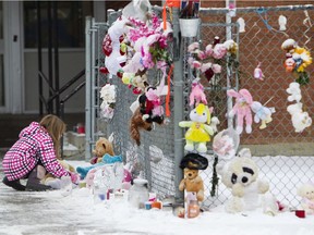 A girl pays her respects at a memorial in front of Racette School in St. Paul, Alberta on Monday, October 29, 2012.  Two children died and a third was seriously injured after a van driven by a man with a known seizure disorder drove into the school. This week, a fatality inquiry report called on the province to make it mandatory for doctors to report patients with medical conditions that impair their driving.
