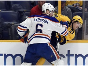 Edmonton Oilers defenseman Adam Larsson checks Nashville Predators right wing James Neal (18) into the boards during the second period of an NHL hockey game Sunday, Feb. 26, 2017, in Nashville, Tenn.