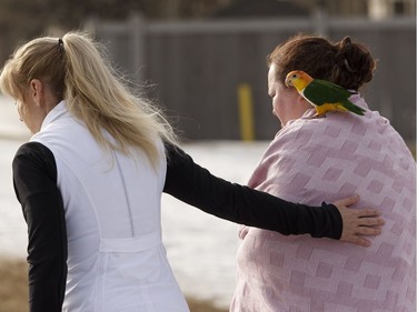 An evacuated resident worried for her birds is helped as Edmonton Fire Rescue Services firefighters battle a blaze at Westridge Estates in Edmonton on Thursday, February 16, 2017. Ian Kucerak / Postmedia