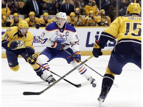 Edmonton Oilers center Connor McDavid (97) moves the puck between Nashville Predators' Calle Jarnkrok (19), of Sweden, and Craig Smith (15) during the first period of an NHL hockey game Thursday, Feb. 2, 2017, in Nashville, Tenn.