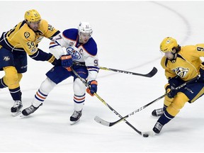 Edmonton Oilers center Connor McDavid (97) maneuvers the puck between Nashville Predators defenseman Roman Josi (59), of Switzerland, and left wing Filip Forsberg (9), of Sweden, during the third period of an NHL hockey game Sunday, Feb. 26, 2017, in Nashville, Tenn. The Predators won 5-4.