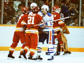 Calgary Flames centre Mike Eaves and defenceman Tony Stiles, foreground left to right, jostle with Edmonton Oilers defenceman Don Jackson, rerar left, and forward Pat Hughes while Flames goalie Rejean Lemelin stands in the background during NHL action at Edmonton's Northlands Coliseum on Feb. 3, 1984.