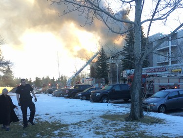 An Edmonton police officer helps a resident evacuate the scene of an apartment fire at Westridge Estates, at 7611 172 St. in west Edmonton, on Thursday, February 16, 2017.