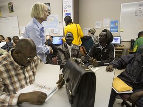 Volunteer Jane Worthington (standing) speaks to potential job applicants during a PCL job fair at the Water Wings offices at Boyle Street Community Services on Tuesday, June 17, 2014.