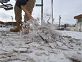 A worker scrapes compacted snow and ice from a sidewalk along 107 Avenue. The number of complaints to the city about ice sidewalks has increased this month.