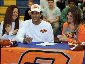 Sherwood Park football athlete Chuba Hubbard, middle, signs a letter of intent with Oklahoma State University at his high school at Bev Facey on February 1, 2017.