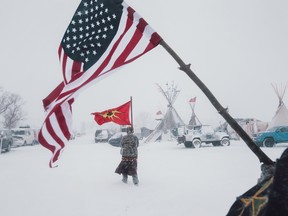 Veterans carry an American and a Mohawk Warrior Society flag through a storm.