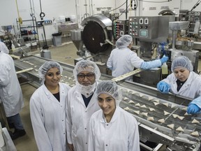 Noorudin Jiwani and his daughters, Khadija (right) and Aliya pose by the samosa production line at Aliya's Foods.